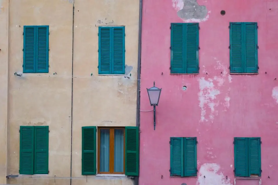 Facciata di un edificio rosa con persiane verdi