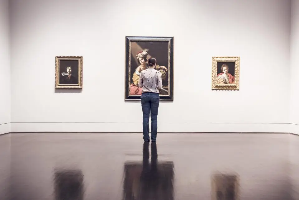 Visitatrice davanti alle opere appese alla parete di una galleria