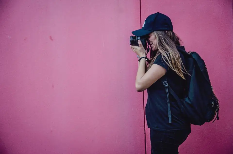 Persona che scatta una fotografia davanti a un muro rosa